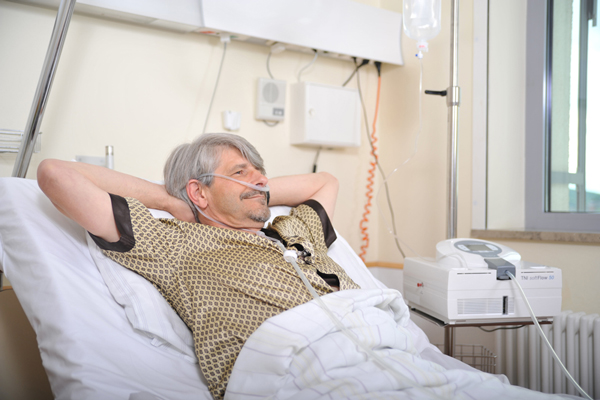 Mann in Krankenhausbett, Nasale und tracheale Anwendung.